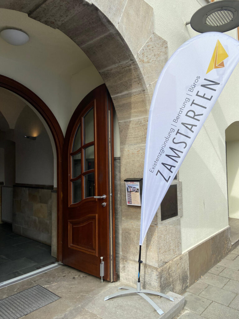 Eine Beachflag, auf der ZamStarten steht, Existenzgründung, Beratung, Büros.